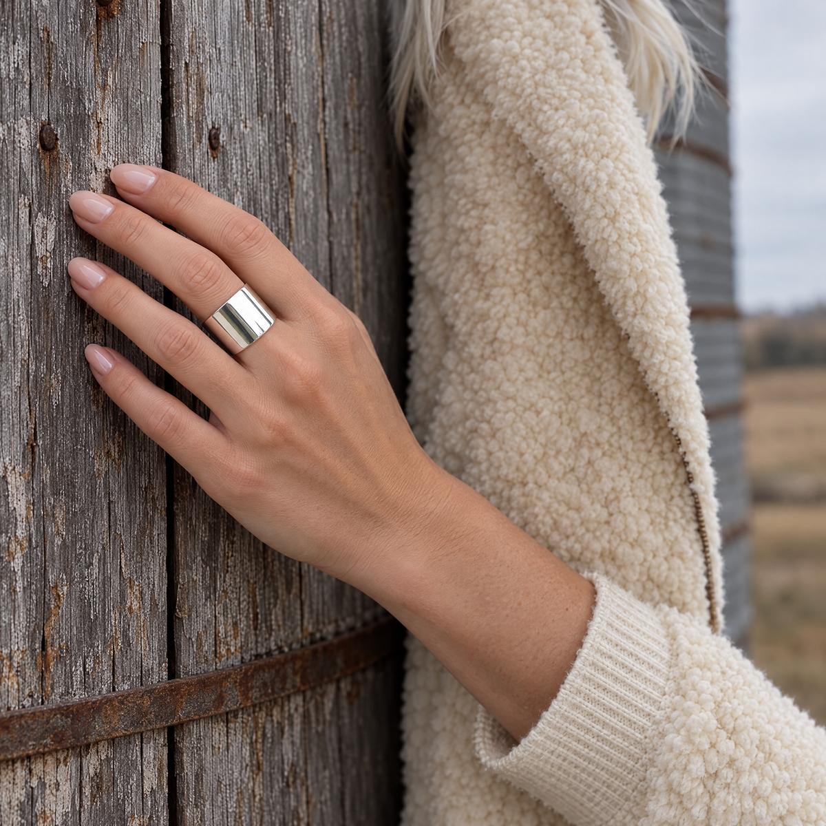 Wide Open Ring worn on hand resting against a grain silo wall
