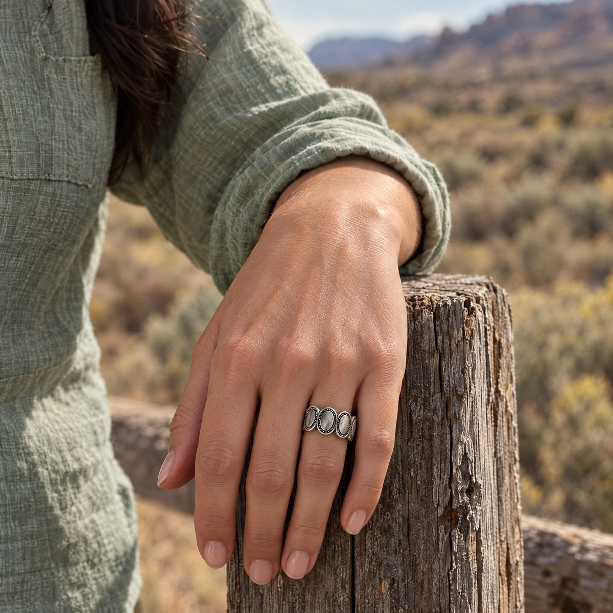 Silver Sage Ring worn on hand resting on a fence post in the desert